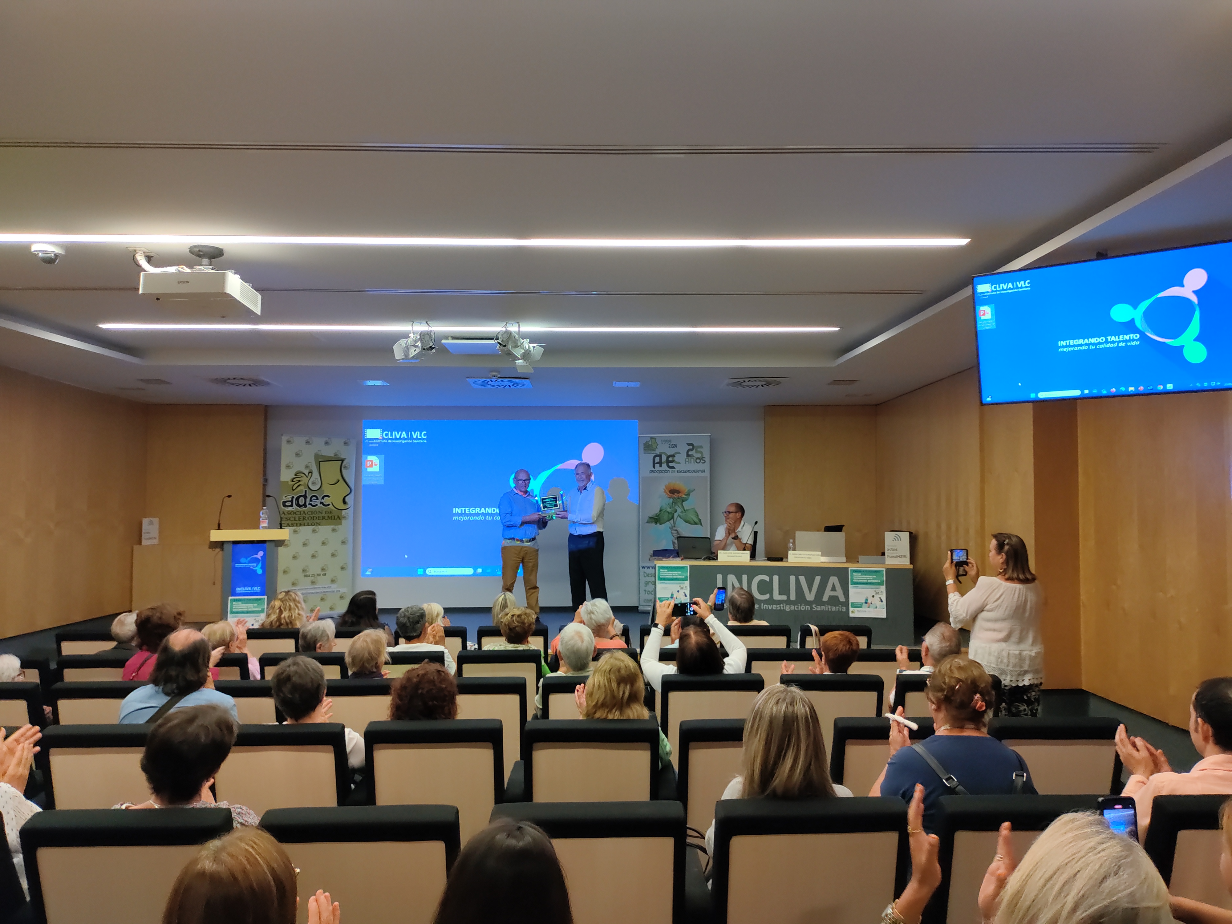 Cartel anunciador de la charla-coloquio organizada por adec en fondo blancocon recuadro s en color azul con letras en contrastre 